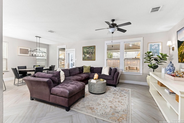 living area with visible vents, baseboards, and ceiling fan with notable chandelier