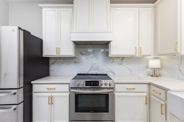 kitchen featuring stainless steel appliances, white cabinets, custom exhaust hood, light stone countertops, and tasteful backsplash