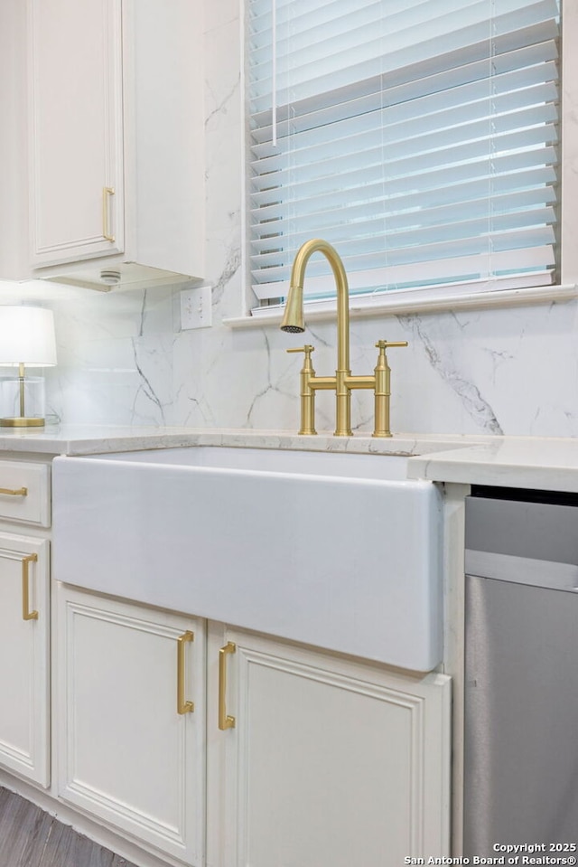 room details featuring tasteful backsplash, a sink, and white cabinets