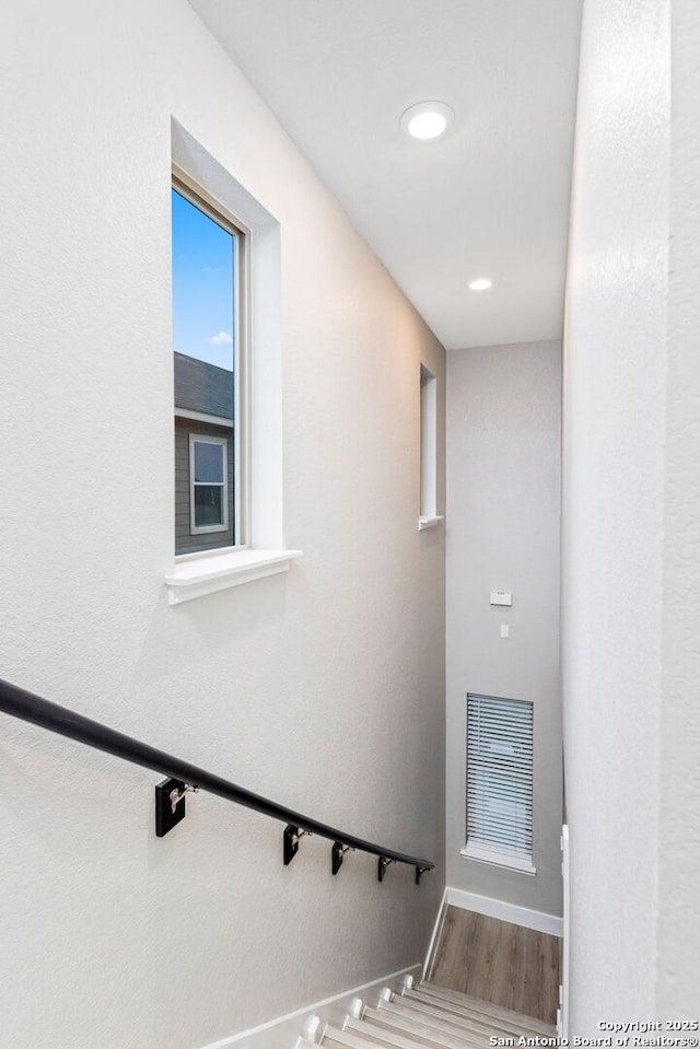 staircase featuring wood finished floors, visible vents, and baseboards