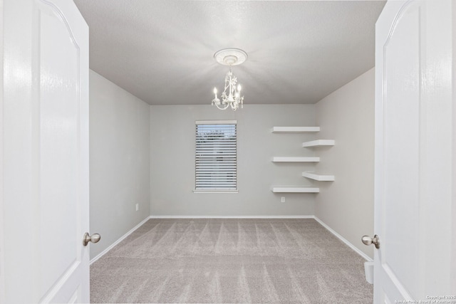 spare room with a chandelier, carpet flooring, and baseboards