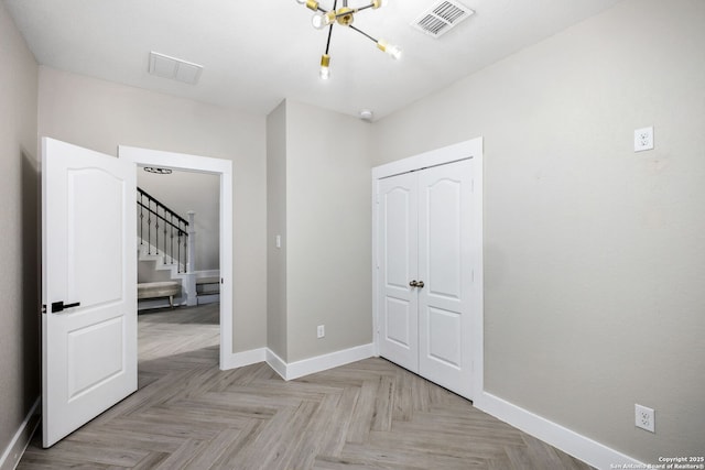 unfurnished bedroom featuring a chandelier, a closet, visible vents, and baseboards