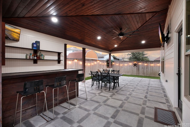 view of patio / terrace featuring fence, visible vents, a ceiling fan, outdoor dry bar, and outdoor dining space