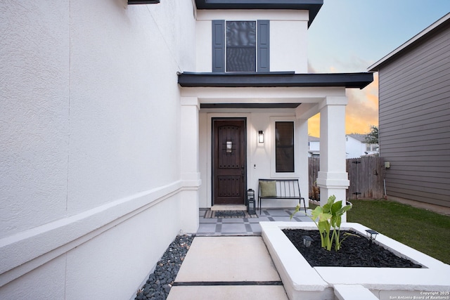 entrance to property with fence and stucco siding