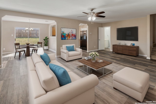 living area featuring arched walkways, wood finished floors, and baseboards