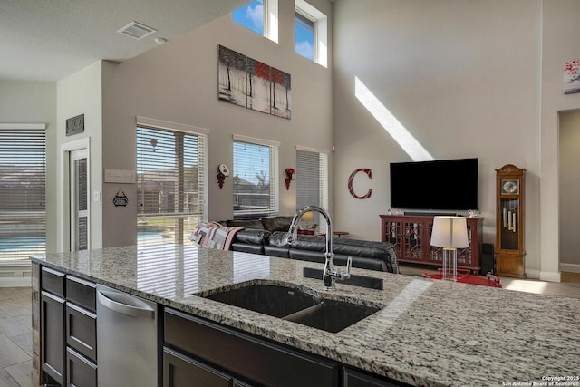 kitchen with light stone countertops, plenty of natural light, open floor plan, and a sink