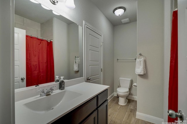 bathroom featuring baseboards, toilet, wood finished floors, curtained shower, and vanity