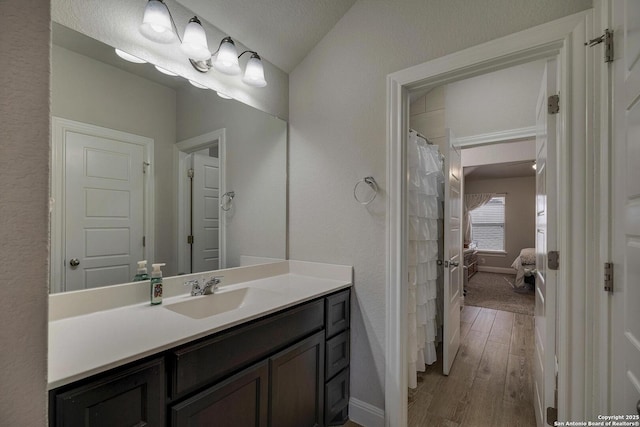 full bath with wood finished floors, vanity, and baseboards