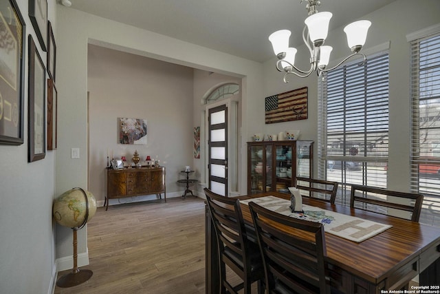 dining room with baseboards, a notable chandelier, and wood finished floors