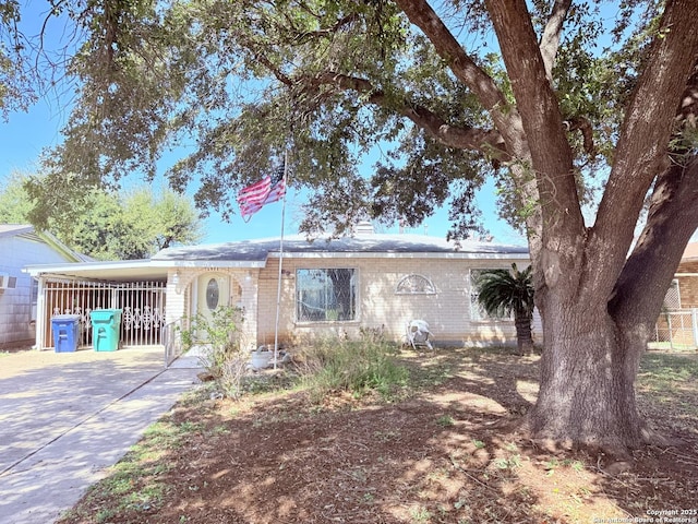 single story home featuring an attached carport, concrete driveway, and brick siding