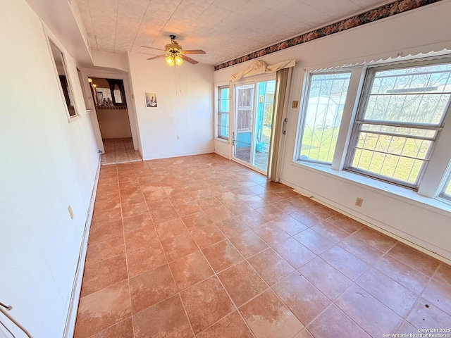 unfurnished room with ceiling fan and baseboards