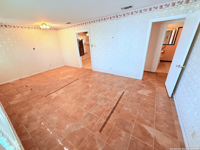 spare room with wallpapered walls, baseboards, and visible vents