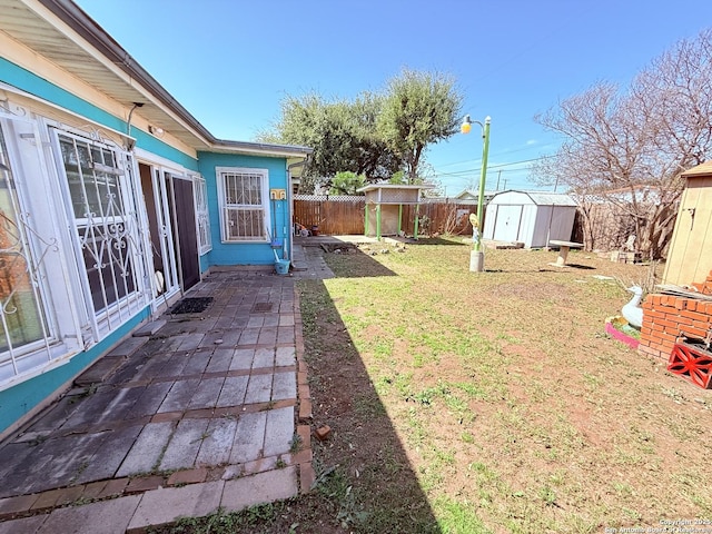 view of yard with a storage shed, a fenced backyard, a patio area, and an outbuilding