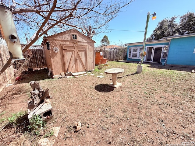 view of yard with an outbuilding, a storage unit, and a fenced backyard