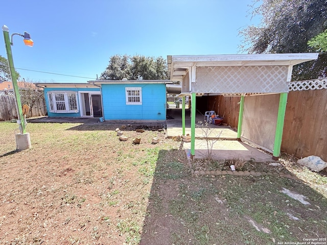 back of property with a carport, fence, and a lawn