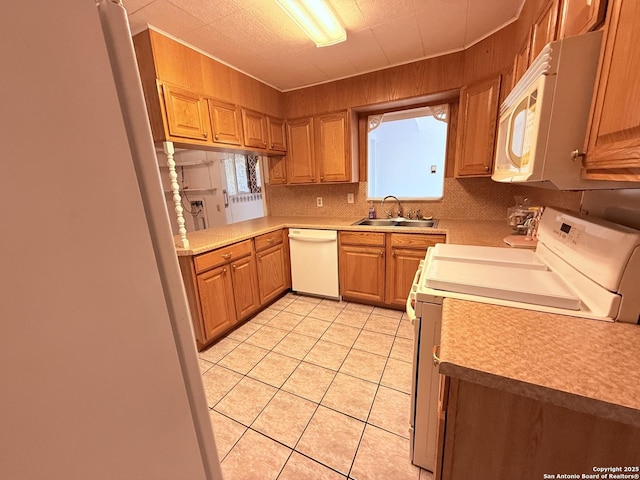 kitchen featuring light tile patterned floors, light countertops, backsplash, a sink, and white appliances