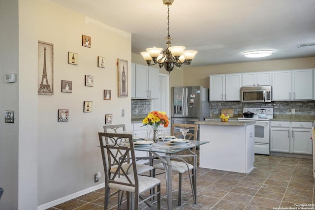 kitchen with a notable chandelier, visible vents, appliances with stainless steel finishes, decorative backsplash, and a center island