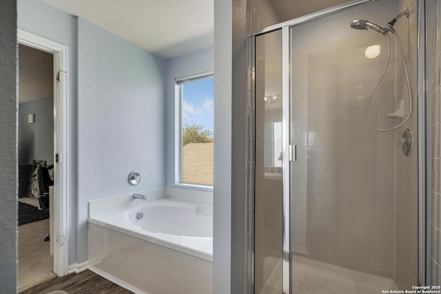 full bathroom featuring a stall shower, a garden tub, a textured wall, and wood finished floors