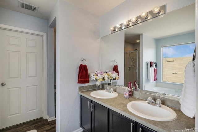 full bathroom featuring wood finished floors, visible vents, a sink, and double vanity