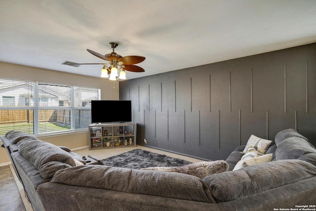 living room with a ceiling fan, visible vents, and baseboards