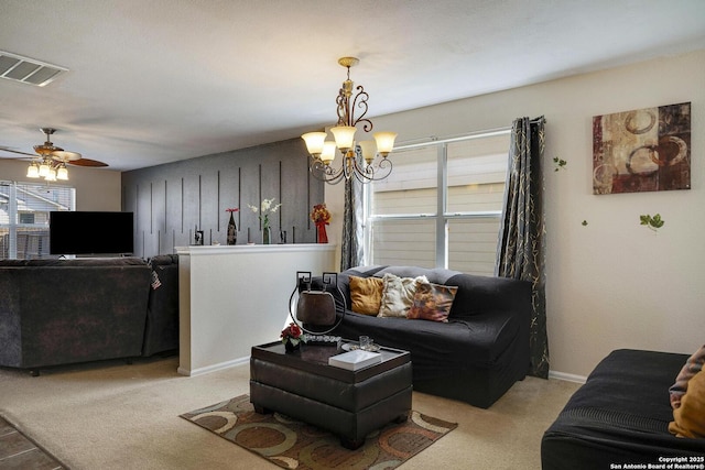 living area with light carpet, baseboards, visible vents, and ceiling fan with notable chandelier