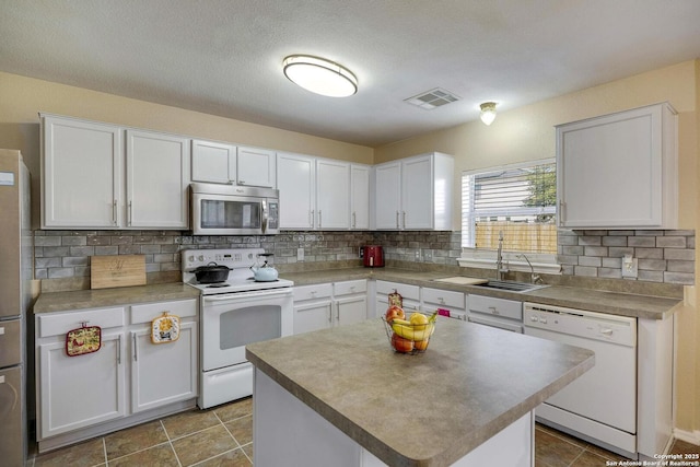 kitchen featuring white appliances, backsplash, a sink, and visible vents