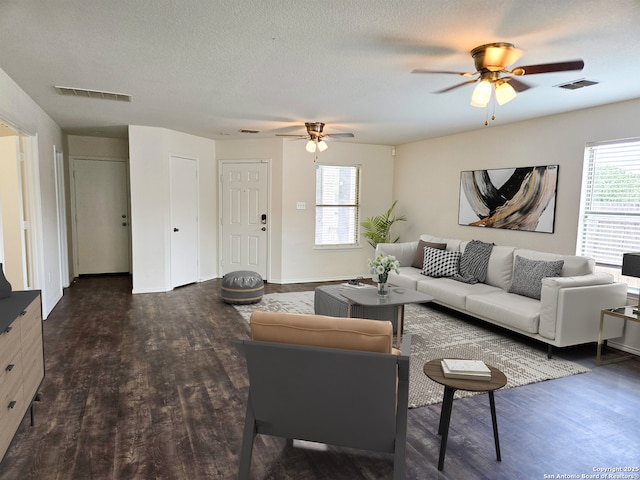 living area with a textured ceiling, ceiling fan, wood finished floors, and visible vents