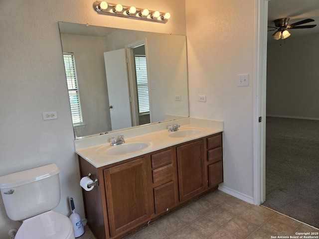 bathroom featuring ceiling fan, double vanity, a sink, and toilet