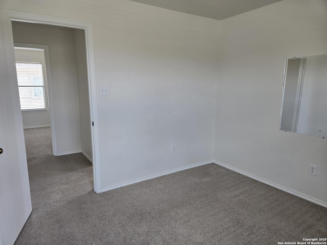 unfurnished room with carpet flooring and baseboards