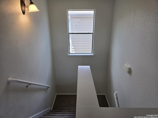 stairs with a textured wall and baseboards