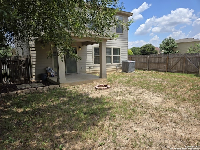 back of house with central AC unit, a fenced backyard, a fire pit, a lawn, and a patio area