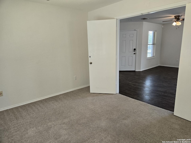 spare room featuring dark carpet, baseboards, and ceiling fan