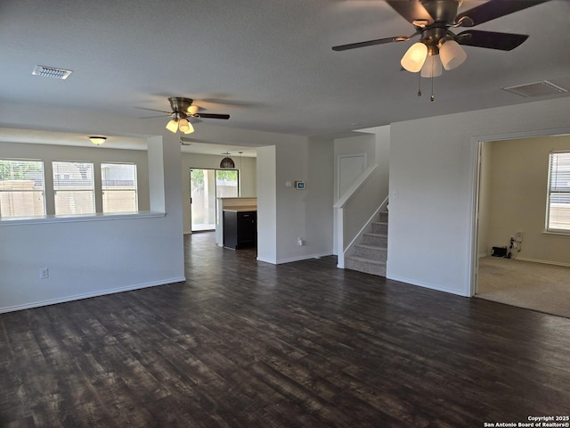 spare room with stairway, visible vents, dark wood finished floors, and a wealth of natural light