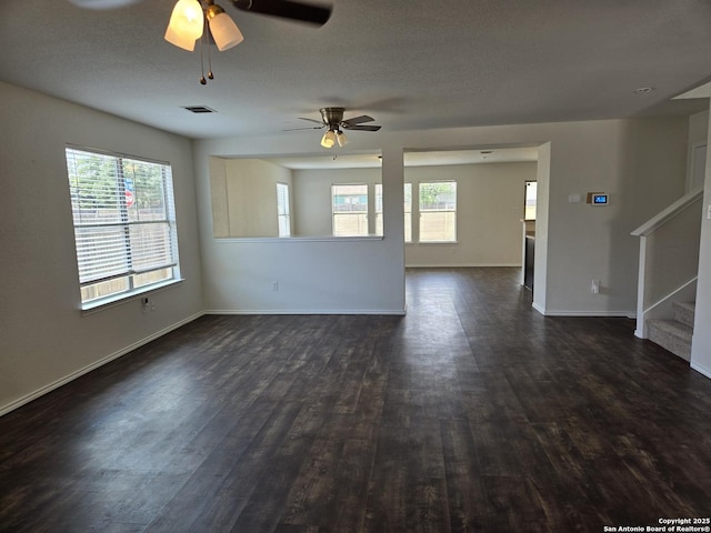 unfurnished living room with stairs, dark wood-style flooring, visible vents, and a healthy amount of sunlight