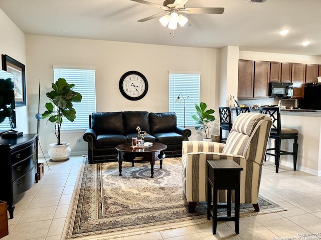 living area with ceiling fan, light tile patterned flooring, visible vents, and baseboards