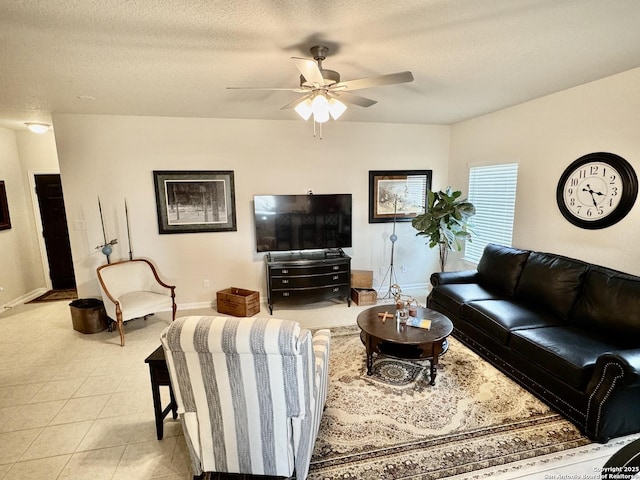 living area featuring light tile patterned flooring, ceiling fan, a textured ceiling, and baseboards