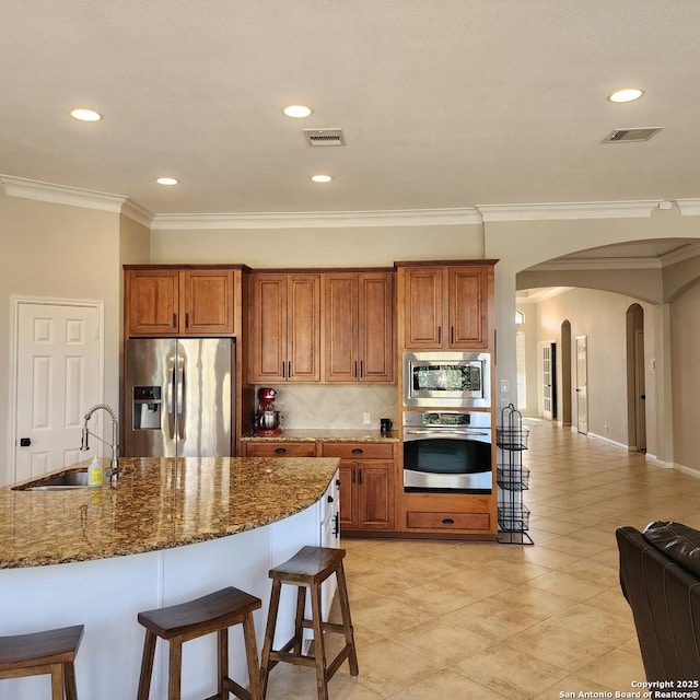 kitchen with a sink, visible vents, stainless steel appliances, and arched walkways