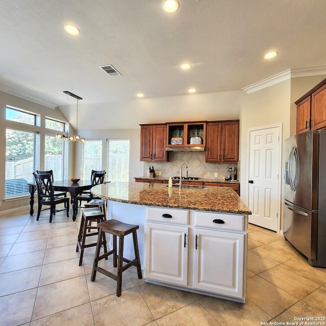 kitchen featuring visible vents, dark stone counters, ornamental molding, stainless steel refrigerator with ice dispenser, and backsplash