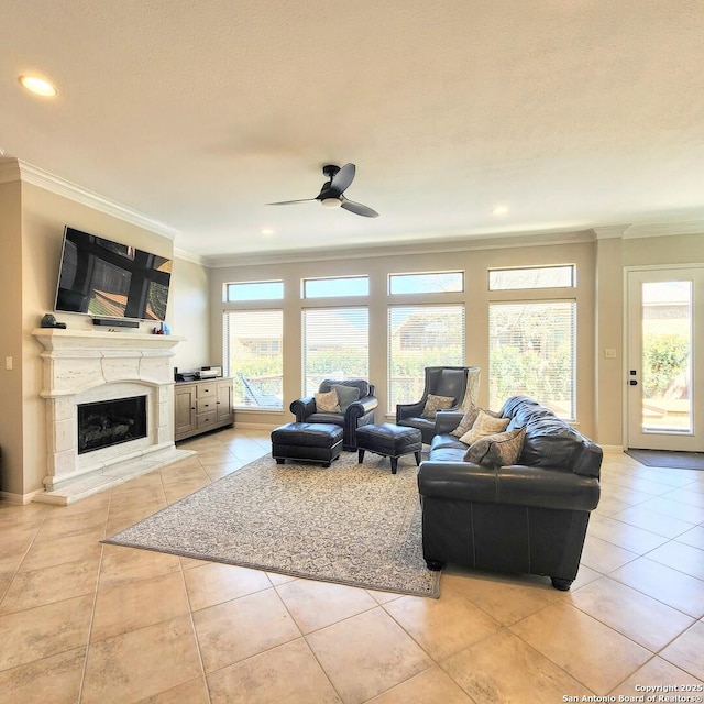 living area with ornamental molding, a ceiling fan, a fireplace, and light tile patterned floors