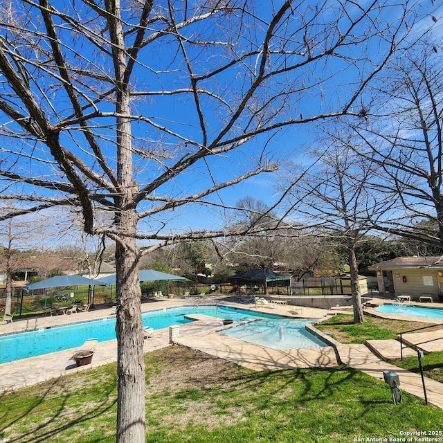 community pool with a patio area and fence