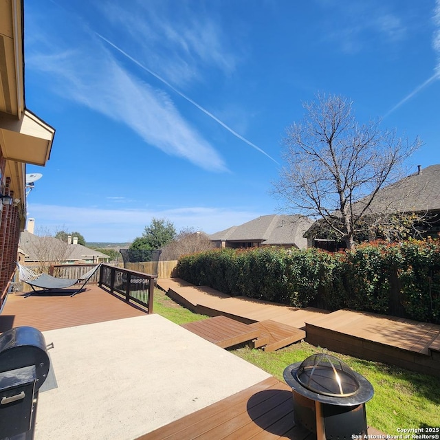 deck with an outdoor fire pit and fence