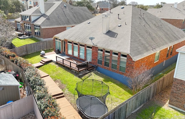 back of house with brick siding, a lawn, a fenced backyard, and a wooden deck