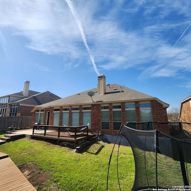 back of property featuring a chimney, fence, a lawn, and brick siding