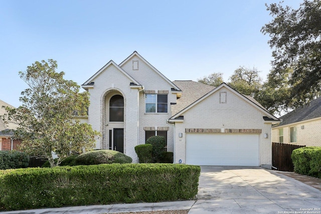 traditional-style home with a garage, brick siding, driveway, and fence