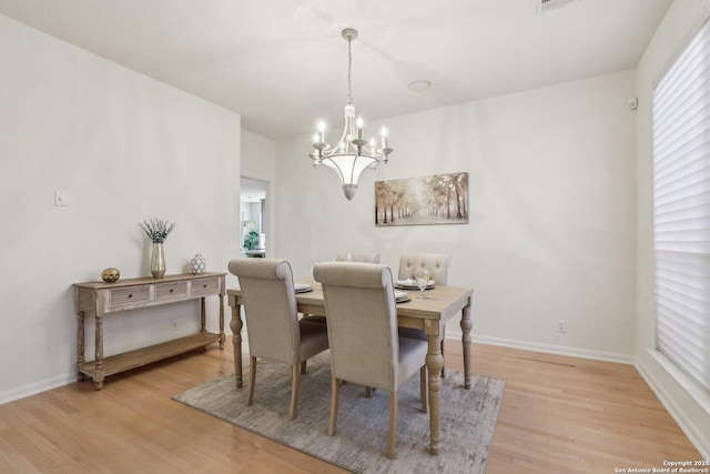 dining space with baseboards, light wood finished floors, and an inviting chandelier