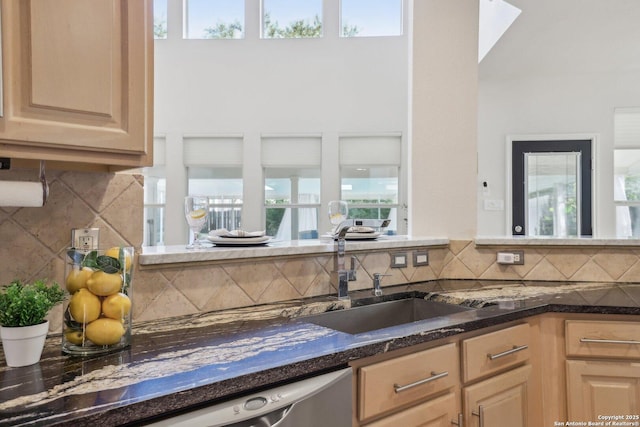 kitchen with decorative backsplash, a sink, stainless steel dishwasher, and light brown cabinetry