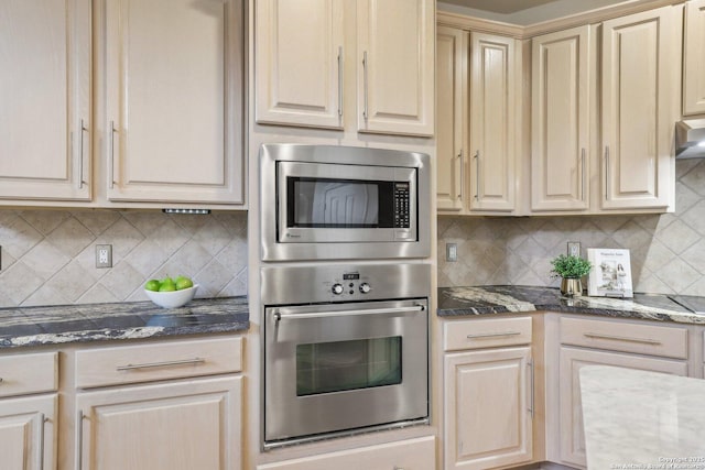 kitchen featuring appliances with stainless steel finishes, dark stone countertops, and backsplash