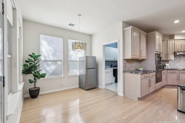 kitchen with under cabinet range hood, visible vents, appliances with stainless steel finishes, light wood-type flooring, and decorative backsplash