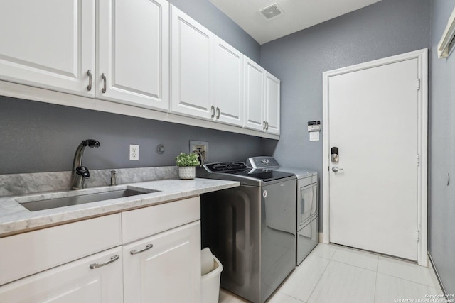 laundry area with cabinet space, visible vents, washer and dryer, a sink, and light tile patterned flooring