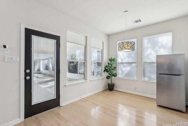 unfurnished dining area featuring light wood finished floors, baseboards, and visible vents